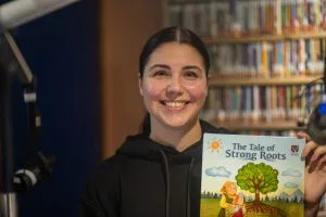 A portrait of a person holding a book while smiling